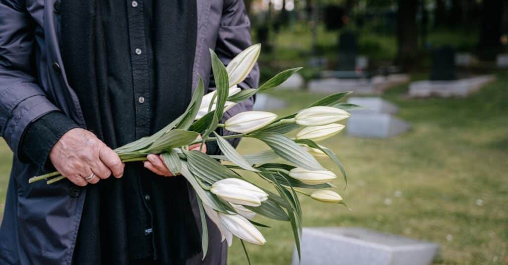 Person holding white flowers in a cemetery