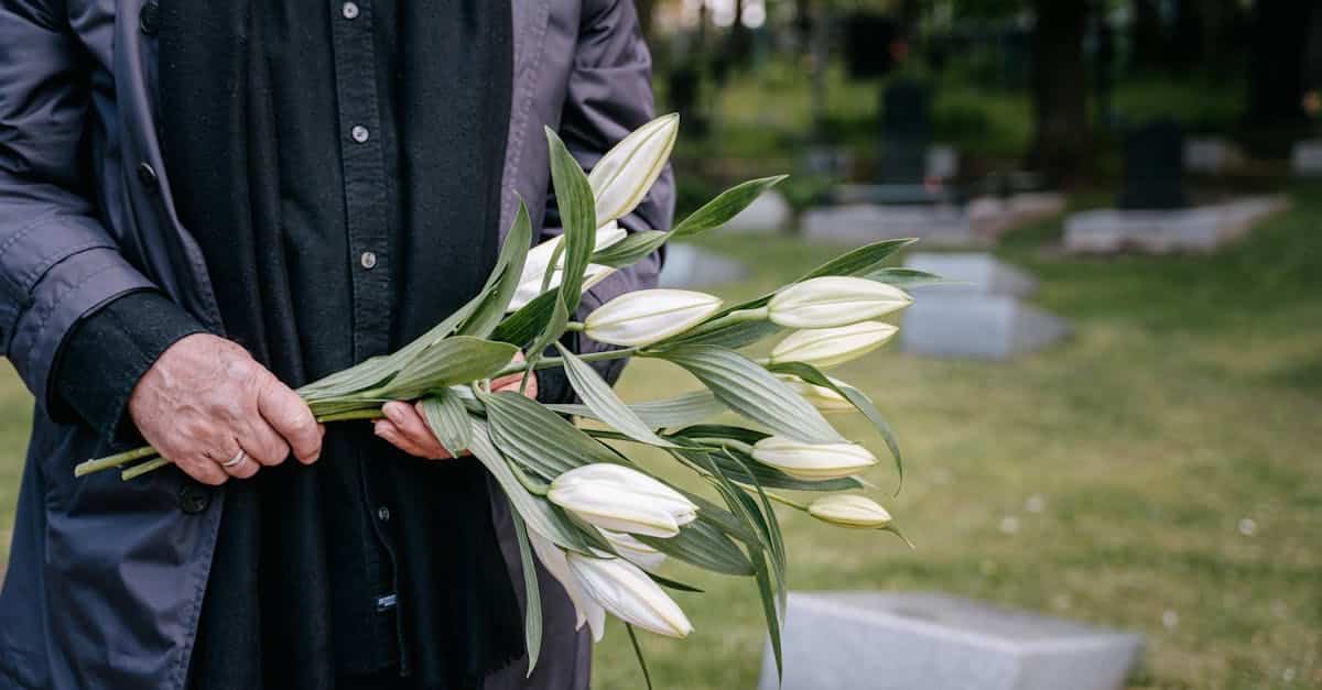 Person holding white flowers in a cemetery